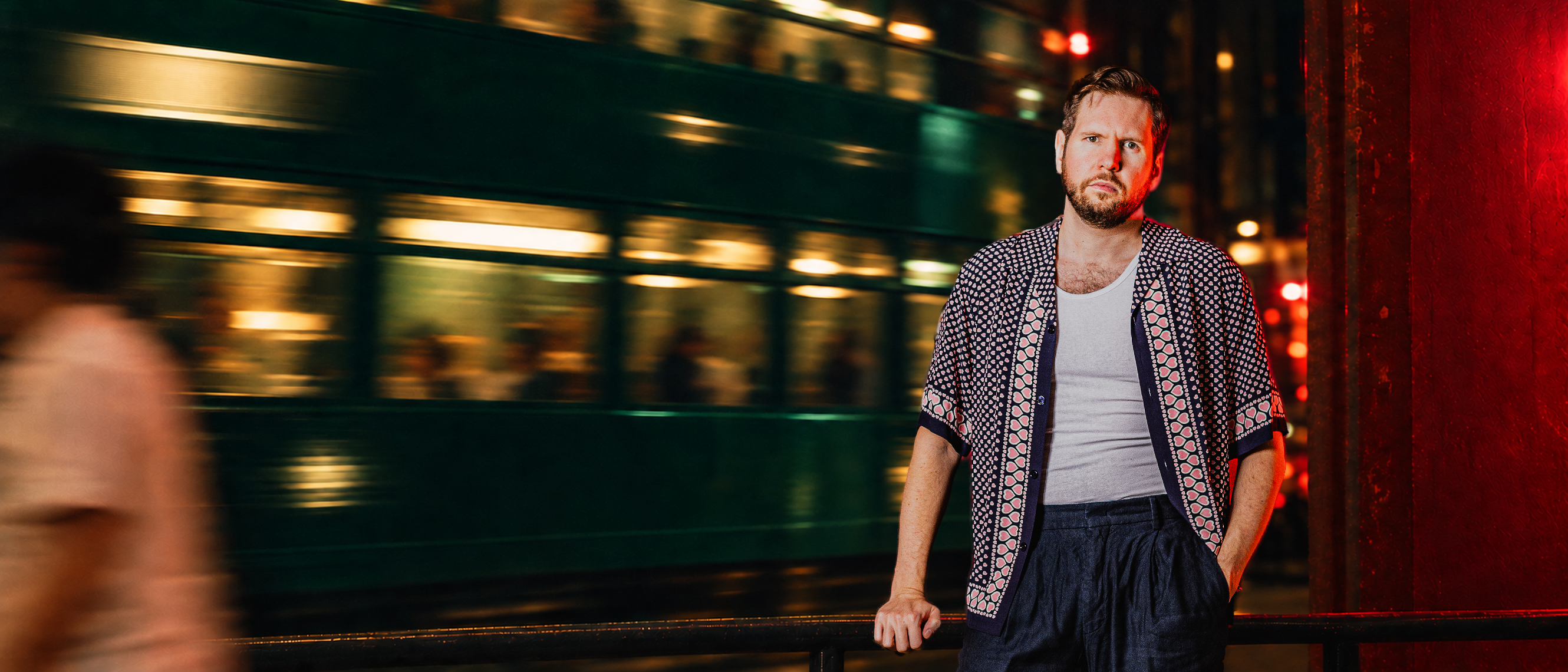 Portrait de Sonny devant une scène urbaine nocturne, lumières rouges et mouvement en arrière-plan.